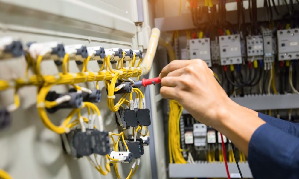 Electricians hands testing current  electric in control panel.